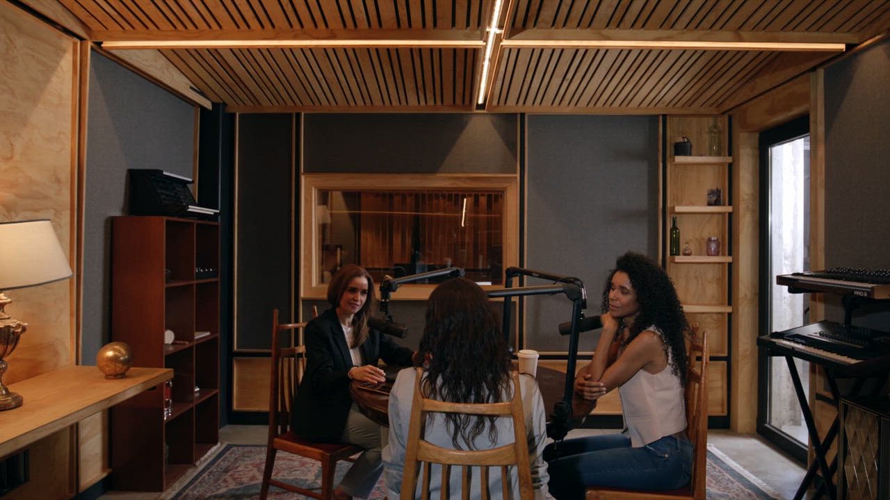 Three women recording a conversation around studio microphones